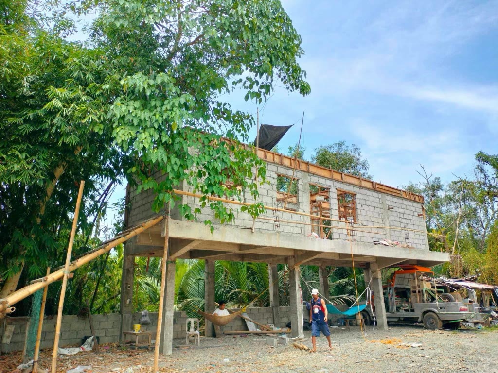 Bamboo scaffolding against the blockwork, with a hammock slung in the open ground floor