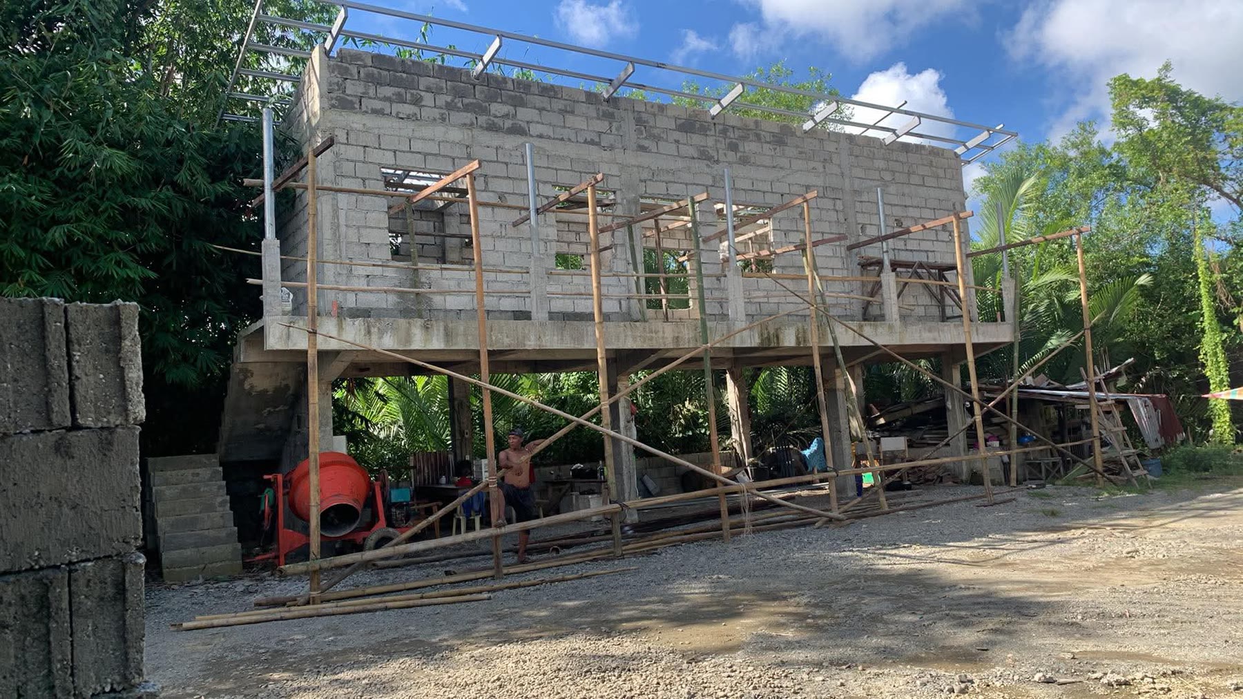 Blockwork walls at full height with timber shoring across the openings and blocks stacked on the ground