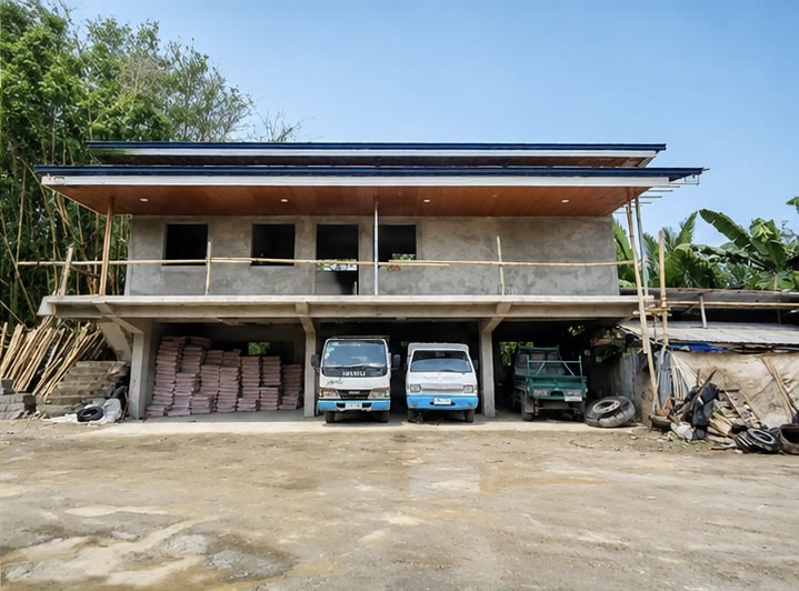 The finished frontage with the roof on, trucks and stacked materials in the parking level underneath