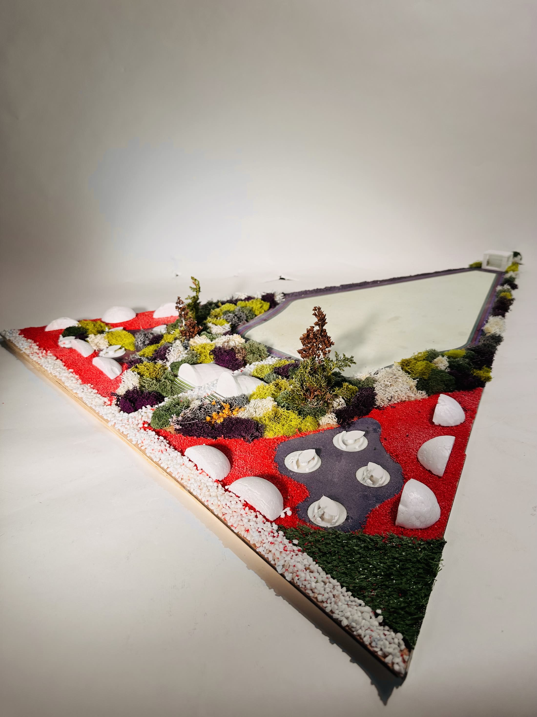 The model from one corner, the red edge of the base running away and the planting massed across it