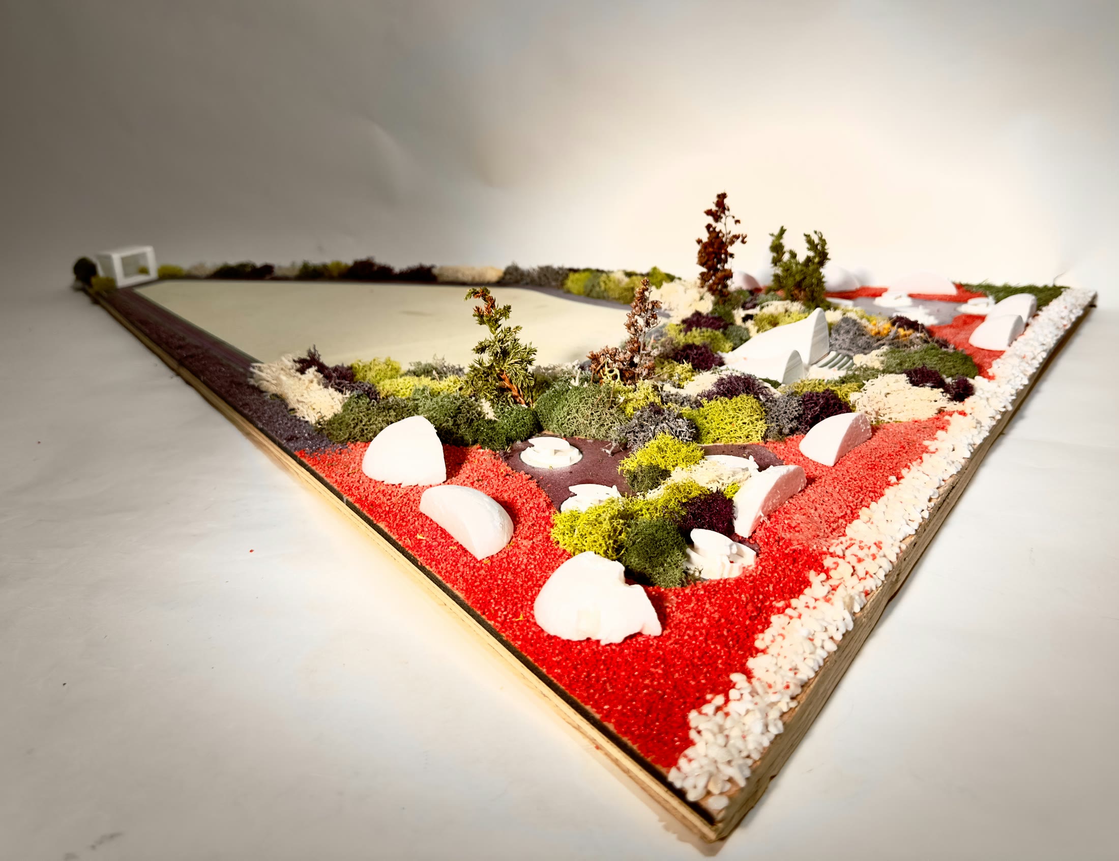 The physical model seen whole on the bench, a triangular base with the lake, the planted grounds and the pavilions in place