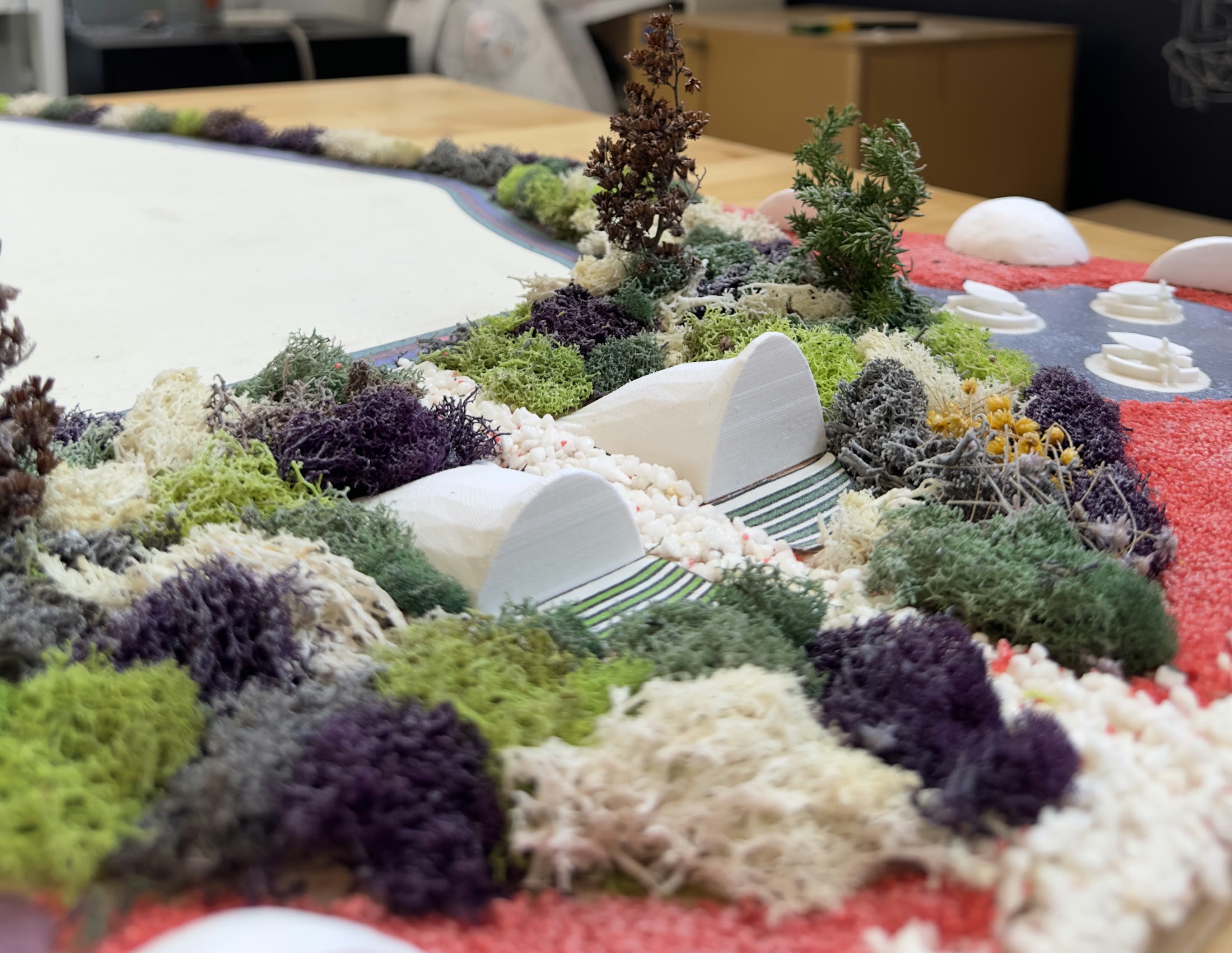 Studio close-up of the model showing the white domes and the layered planting around them